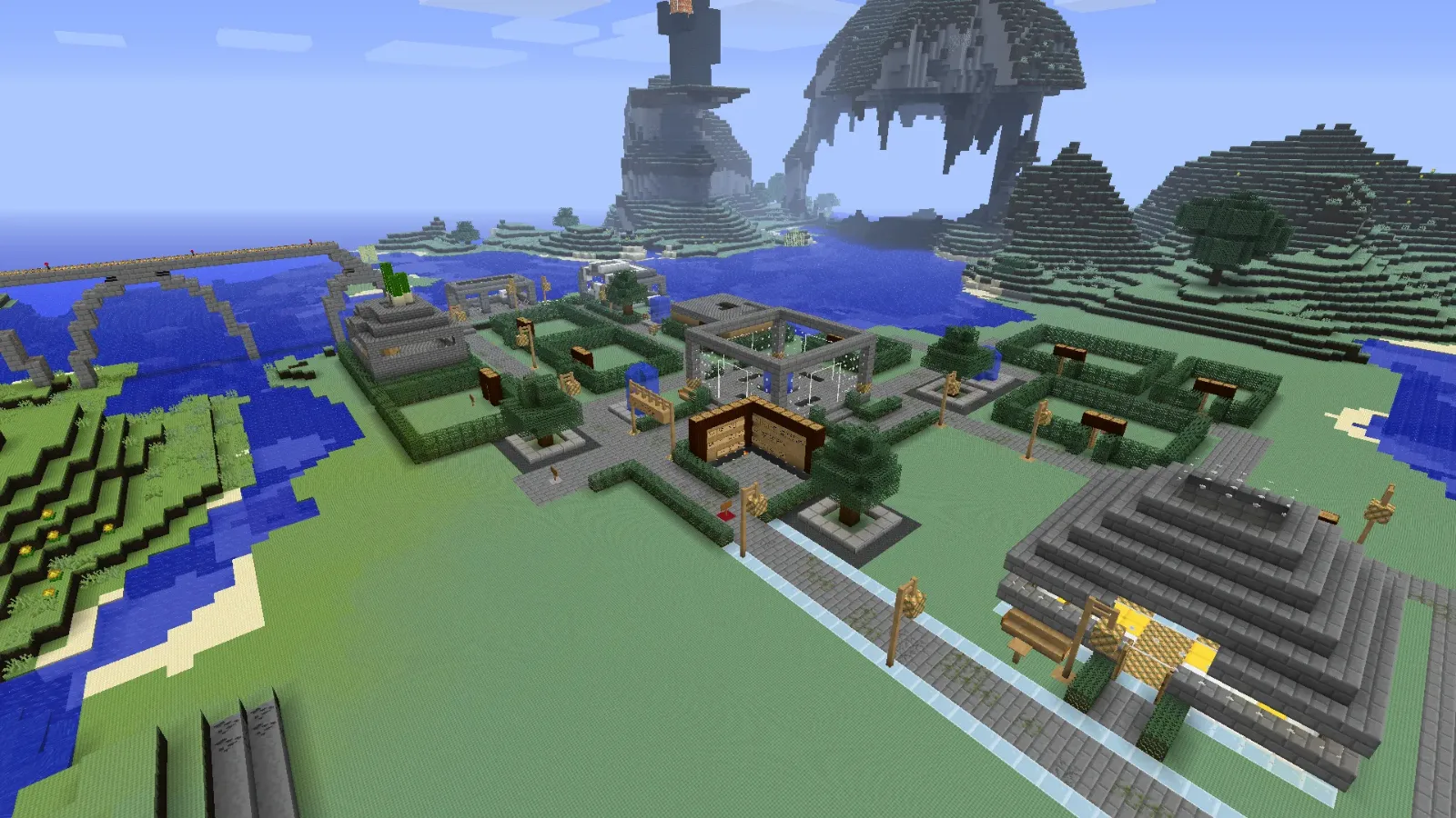 TerraScape's spawn town: hedge-lined plots, stone paths and buildings beside a river, with tall rock formations behind
